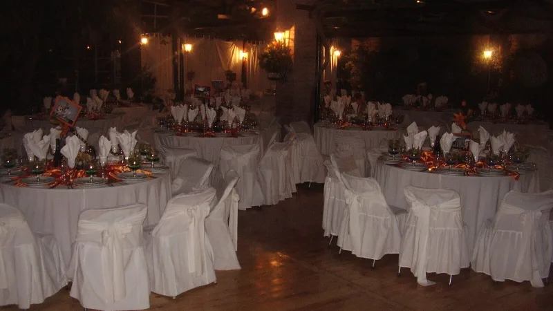 Banquete de matrimonio con sillas vestidas en blanco y centros de mesa en tonos cobre